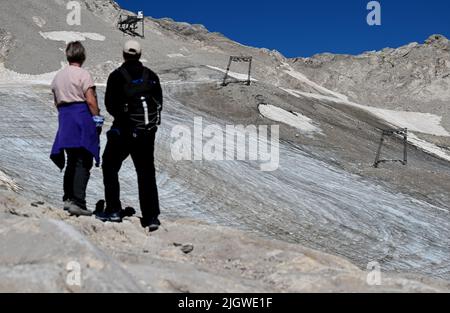 Grainau, Deutschland. 13.. Juli 2022. Wanderer schauen sich die Überreste des nördlichen Schneefernergletschers auf dem Zugspitzplatt an. Die warmen Temperaturen beeinflussten in diesem Sommer die Reste des Gletschers auf der Zugspitze. Quelle: Angelika Warmuth/dpa/Alamy Live News Stockfoto