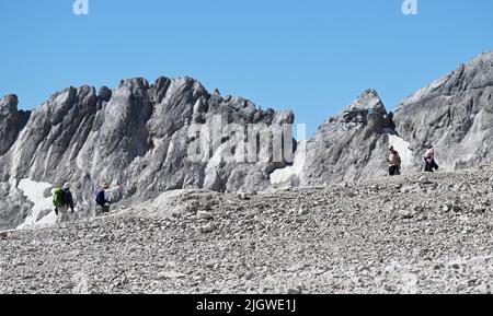 Grainau, Deutschland. 13.. Juli 2022. Wanderer sind auf dem Zugspitzplatt unterwegs. Die warmen Temperaturen belasten in diesem Sommer den Restgletscher des Nördlichen Schneeferners auf der Zugspitze. Quelle: Angelika Warmuth/dpa/Alamy Live News Stockfoto