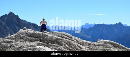 Grainau, Deutschland. 13.. Juli 2022. Ein Wanderer genießt die Fernsicht auf dem Zugspitzplatt. Die warmen Temperaturen beeinflussten in diesem Sommer den Gletscherrest des Nördlichen Schneeferners auf der Zugspitze. Quelle: Angelika Warmuth/dpa/Alamy Live News Stockfoto