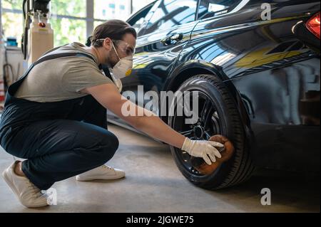 Erfahrener Auto-Detailer, der den Autoreifen abpuffert Stockfoto