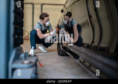 Werkstattmitarbeiter, der das Rad des Fahrzeugs abpuffert Stockfoto