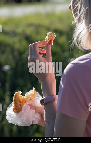 Frau bricht im Park ein Stück Brötchen ab. Hochwertige Fotos Stockfoto