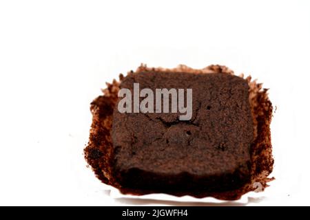 Süßes Brownie-Schokoladenkuchenstück isoliert auf weißem Hintergrund, selektiver Fokus von Brownie-Scheibe mit Kakaopulver auf einem üblichen Butterpapier Stockfoto