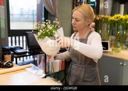 Blumengeschäft Manager entfernt überschüssige Blätter auf einem Strauß mit Gartenscheren Stockfoto