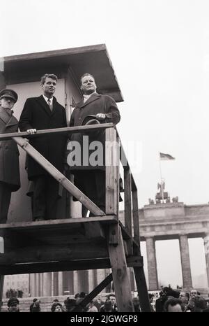 Robert F. Kennedy mit Gattin Ethel in Berlin 1962 - Regierender Bürgermeister Willy Brandt (rechts) mit Robert F. Kennedy auf einem Aussichtsturm an der Schandmauer vor dem Brandenburger Tor, Berlin, Deutschland 1962. Stockfoto