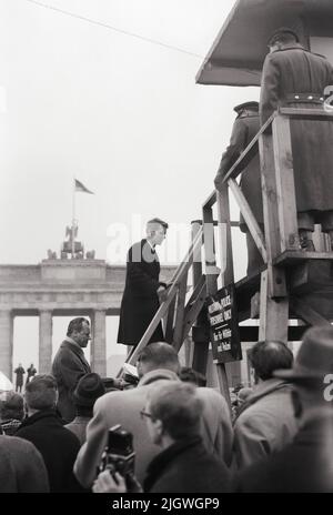 Robert F. Kennedy mit Gattin Ethel in Berlin 1962 - Regierender Bürgermeister Willy Brandt (hinten) besteigt mit Robert F. Kennedy einen Aussichtsturm an der Schandmauer vor dem Brandenburger Tor, Berlin, Deutschland 1962. Stockfoto