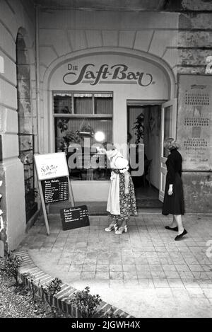 In der Saftbar - Original-Bildunterschrift: Die erste und einzige Saft-Bar Berlins wurde gestern an der Ecke Neue Ansbacher- Ecke Regensburgerstraße eröffnet. Hier kann man vom Spinat- bis zur Mohrrübensaft frisch aus der Presse alles erhalten. Unser Bild zeigt: Die neue Saft-Bar von aussen, Berlin, Deutschland 1955. Stockfoto