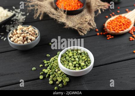 Grüne Erbsen und uralte Getreideprodukte auf einem dunklen, rustikalen Hintergrund. Glutenfreies Getreide gesundes Geflügel. Der Trend zu gesunden Lebensmitteln Stockfoto