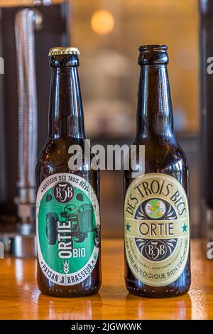 Zwei Etikettenversionen des "Ortie" (Nesselsee)-Bieres stehen nebeneinander in der Brasserie des Trois Becs in Gigors-et-Lozeron, Drôme, Frankreich: Das neue Design zeigt einen Traktor, ein Symbol für die doppelte Rolle der Brauerei als Farm und Brauerei. Der Agrarwissenschaftler Emmanuel Feraa gründete die Bio-Brauerei 2015. Sie baut einen Großteil ihres eigenen Hopfens und Gerstes vor Ort an. Stockfoto