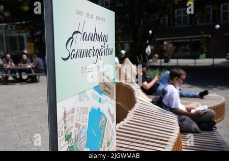 Hamburg, Deutschland. 13.. Juli 2022. Passanten genießen die Sonne in einem Hamburger Sommergarten am Georg-Elser-Platz in der Innenstadt. Die Innenstadt der Hansestadt verwandelt sich in eine grüne Oase. Sieben Einkaufsviertel verwandeln leerstehende Grundstücke in kleine Gärten. Kredit: Marcus Brandt/dpa/Alamy Live Nachrichten Stockfoto