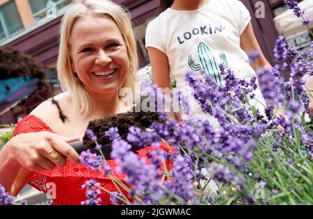 Hamburg, Deutschland. 13.. Juli 2022. Moderatorin Nova Meierhenrich pflanzt während der Eröffnung des Hamburger Sommergartens Lavendel in einen Blumentopf. Die Hansestadt verwandelt sich in eine grüne Oase. Sieben Einkaufsviertel verwandeln leerstehende Flächen in kleine Gärten. Kredit: Marcus Brandt/dpa/Alamy Live Nachrichten Stockfoto