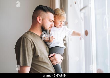 Multinationale Familie, junger Mann Vater mit Baby Mädchen auf Fensterbank Blick auf Fenster zu Hause Stockfoto