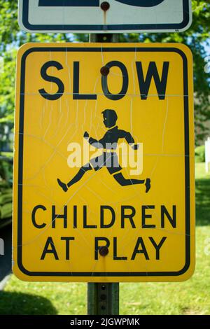 Nahaufnahme von Slow Children at Play, schwarzes und orangefarbenes Schild am Straßenrand Stockfoto