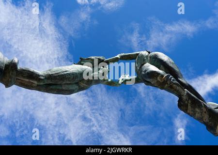 Bronzestatue gegen den blauen Himmel der beiden Liebenden in Playa del Carmen, Mexiko. Von unten aufgenommen. Statuen in der Hand Stockfoto