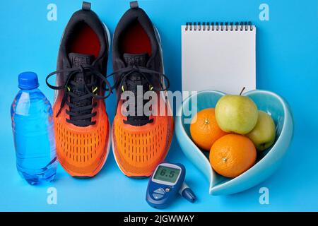 Orangefarbene Turnschuhe, ein Notizbuch-Tagebuch, ein Glucometer, eine Flasche Trinkwasser und Früchte. Konzept eines gesunden Lebensstils zur Aufrechterhaltung normaler Blutglucos Stockfoto