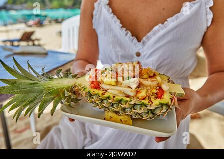 Am Strand von Phuket wird gebratener Reis mit Meeresfrüchten in einer Ananas serviert Stockfoto