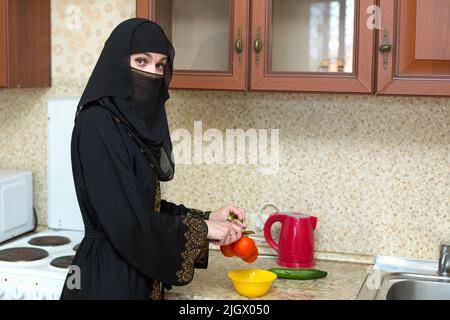 Muslimische Frau, die zu Hause in der Küche Hausarbeit leistet. Stockfoto