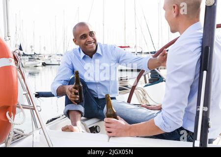 Ein paar Jungs in blauen Hemden und Jeans plaudern auf einer privaten Yacht im Hafen Stockfoto