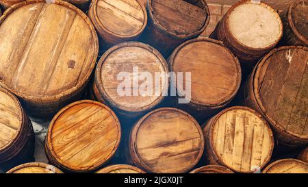 Fässer Wein im Keller. Eichenfässer für die Lagerung von Cognac aus nächster Nähe. Herstellung von Cognac auf die alte Weise. Alterung alkoholischer Getränke in Holzbalken Stockfoto