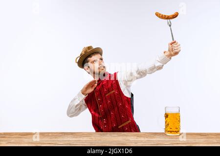 Junger expressiver Mann im Hut, in festlicher bayerischer oder deutscher Tracht mit großem Bierglas. Alkohol, Traditionen, Feiertage, Oktoberfest Stockfoto