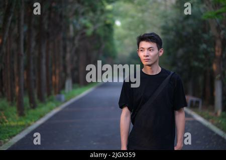 Porträt eines hübschen jungen chinesischen Mannes im Naturwaldpark Stockfoto