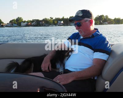 MANN MIT HUND AUF DEM BOOT Stockfoto