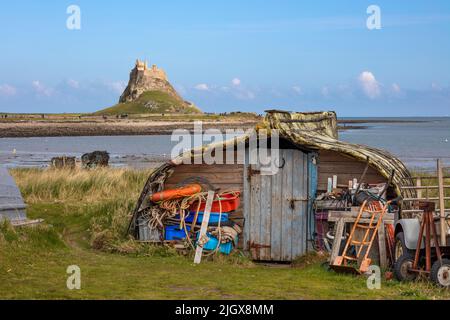 Umgedrehten Bootsrumpf zur Aufbewahrung von Fischerausrüstung mit Lindisfarne Castle dahinter, Holy Island, Northumberland, England, Vereinigtes Königreich, Europa Stockfoto