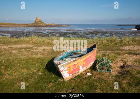 Altes Holzboot an Land mit Lindisfarne Castle bei Ebbe, Holy Island, Northumberland, England, Vereinigtes Königreich, Europa Stockfoto