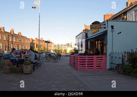 Menschen, die draußen auf dem Bürgersteig im trendigen Innenstadtviertel von Stoneybatter, Dublin, Irland, essen, Juli 2022 Stockfoto