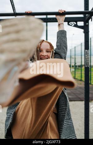 Verspieltes Teenager-Mädchen mit an einer hohen Stange hängenden Furcht und tritt ihren Stiefel in die Kamera. Stockfoto