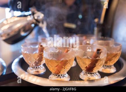 Ein Tablett mit heißen Toddies wird mit ansteigendem Dampf gegossen Stockfoto