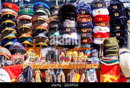 Berlin, 21. Juni 2022: Mützen, Hüte und Souvenirs mit den Insignien der Sowjetunion und der Deutschen Demokratischen Republik an einem Stand in der Nähe von CHEC Stockfoto