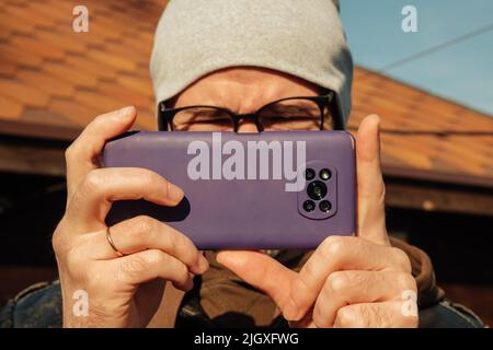 Junger lächelnder, zwangloser Mann, der ein Foto von Ihnen gemacht hat Stockfoto