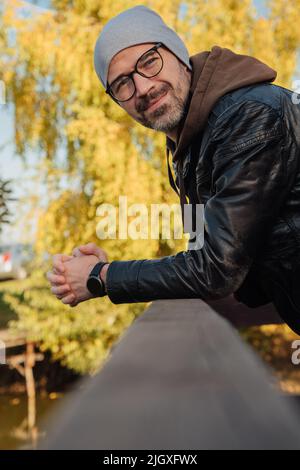 Schöner lächelnder Mann im Jackenkittel im Herbst Stockfoto