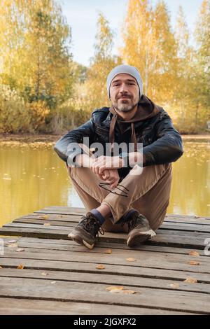 Schöner lächelnder Mann im Jackenkittel im Herbst Stockfoto