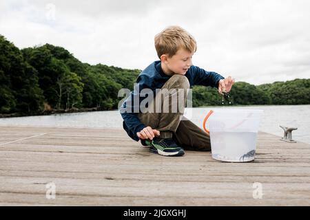 Junge glücklich hält eine Krabbe, die er beim Angeln auf dem Dock gefangen Stockfoto