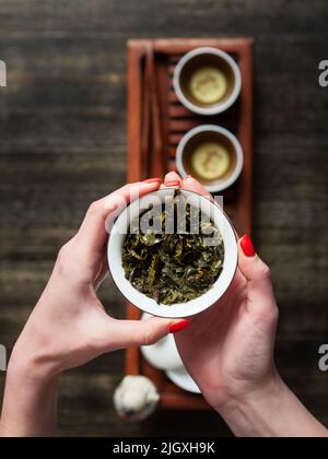 Hände, die Chawan (Teeschale) mit grünem Oolong halten. Draufsicht. Stockfoto
