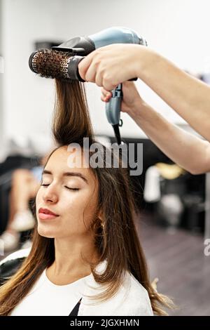 Barber bläst den Kunden Haare nach dem Haarschnitt im Friseurladen aus Stockfoto