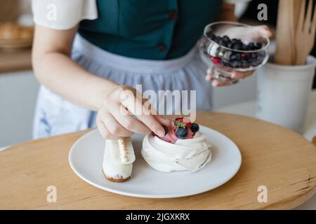 Mädchen Konditor fügt eine Beere zum Kuchen Stockfoto