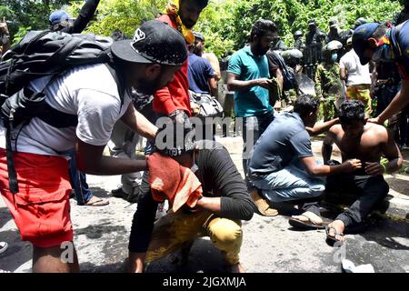 Colombo, Sri Lanka. 13.. Juli 2022. Demonstranten reagieren während eines Zusammenstoßes vor dem Büro des srilankischen Premierministers Ranil Wickremasinghe während eines Protestes, der seinen Rücktritt forderte, aufgrund von Tränengas, nachdem Präsident Gotabaya Rajapaksa am Mittwoch, dem 13. Juli 2022, inmitten der Wirtschaftskrise des Landes in Colombo, Sri Lanka, geflohen war. Tausende von regierungsfeindlichen Demonstranten stürmten Stunden nach seiner Ernennung zum amtierenden Präsidenten in das Büro des Premierministers Ranil Wickremesinghe von Sri Lanka. Foto von Kumara De Mel/ Credit: UPI/Alamy Live News Stockfoto