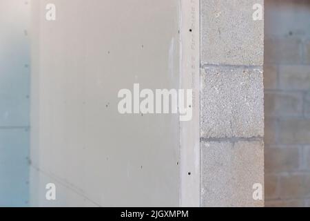 Trockenbauplatten, teilweise auf verzinkten Stahlrahmenstreben in einem Geschäftsgebäude installiert, das auf einer Wand aus Zunder-/Betonblöcken aufgestellt ist. Stockfoto