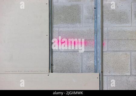 Trockenbauplatten, teilweise auf verzinkten Stahlrahmenstreben in einem Geschäftsgebäude installiert, das auf einer Wand aus Zunder-/Betonblöcken aufgestellt ist. Stockfoto