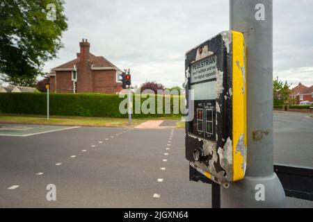 Pelican (historisch Pelicon) auf einer britischen Straße überqueren. Fußgänger drücken die Taste und warten auf das entgegengesetzte Signal Stockfoto