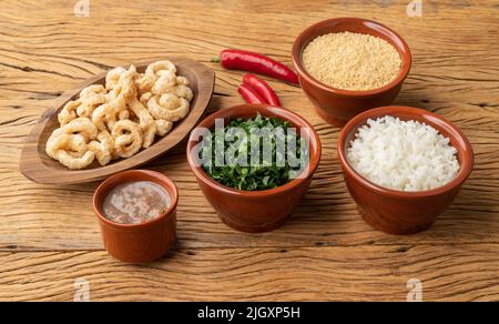 Typische brasilianische Feijoada-Beilagen. Reis, Grünkohl, Pfeffer, Farofa und Knistern. Stockfoto