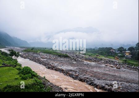 Während der Regenzeit fließt der Gebirgsfluss Balason hinunter zur Gangetic-Ebene mit starken Strömungen aus den Ausläufern des Himalaya in der terai-Region Dudhia, Westbengalen. Die Farbe des Flusses wird braun, weil der riesige Kiessand mit dem Wasser vom Berg schwimmt. In der Trockenzeit wird das Flussbett trocken und verwandelt sich in den Schießstand des TOCHTERTRAININGSZENTRUMS Border Security Force, North Bengal (STC BSF NB), bekannt als Dudhiya Schießstand. Indien. Stockfoto