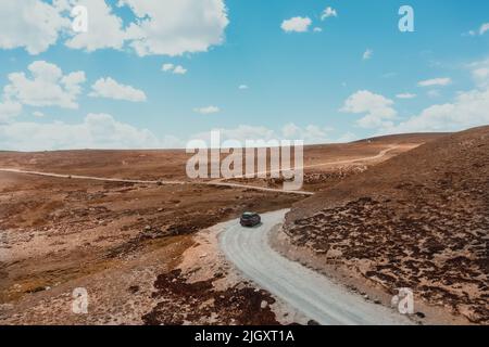 SUV fährt an einem sonnigen Sommertag im Norden Pakistans auf einer kurvenreichen Straße des Deosai-Nationalparks Stockfoto