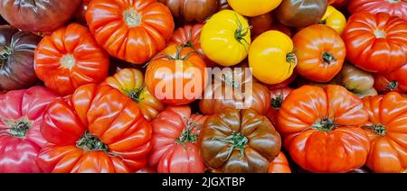 Erbstück Tomaten lose auf einem Marktstand mit unterschiedlicher Größe, Formen und Texturen von direkt oben gesehen angezeigt. Stockfoto