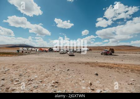 Autos parkten an einem Rastplatz mit Zelten im trostlosen, trockenen Gelände des Deosai-Nationalparks in Pakistan Stockfoto