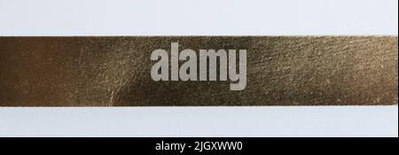 Glänzendes Gold Farbe schmalen Strape auf weißem Papier Textur Hintergrund Stockfoto