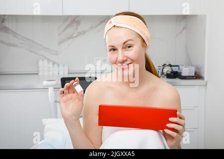 Eine Frau hält ein kosmetisches Produkt in der Hand. Injektionslösung. Stockfoto